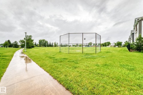Expansive green space featuring a paved walking path, a baseball backstop, and mature trees - 17 4137 76 Street, Edmonton, AB 