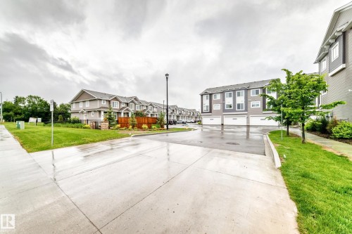 Exterior view featuring a multi-story building with gray siding and white trim accents - 17 4137 76 Street, Edmonton, AB 