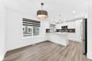 Open-concept kitchen and dining area featuring wood-finish flooring, white cabinetry, stainless steel appliances, a center island with sink, and modern pendant lighting - 17 4137 76 Street, Edmonton, AB 