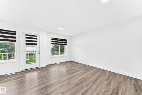 Spacious room featuring wood-finish flooring, white walls, and contemporary window treatments - 17 4137 76 Street, Edmonton, AB 