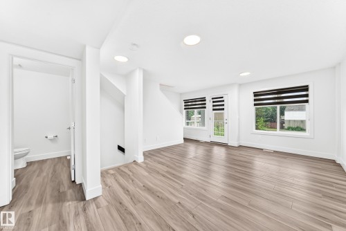 Spacious interior featuring wood-finish flooring, recessed lighting, and bright white walls - 17 4137 76 Street, Edmonton, AB 