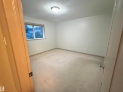 Neutral-toned room featuring a single window with blinds, carpet flooring, a flush-mount ceiling light fixture, and light-colored walls with baseboards - 