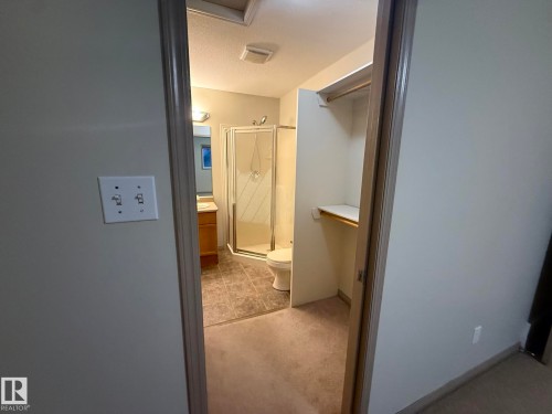 Bathroom featuring a glass-enclosed shower, a vanity with wood-finish cabinetry, and a toilet - 1978 Tomlinson Green Green, Edmonton, AB 