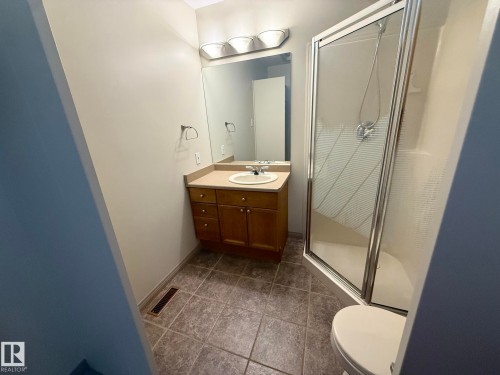 Bathroom featuring a vanity with an integrated sink, shower stall with clear glass enclosure, and tiled flooring - 1978 Tomlinson Green Green, Edmonton, AB 