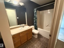 Bathroom featuring a light wood-finish vanity with ample storage, a white oval sink, and a large wall-mounted mirror - 