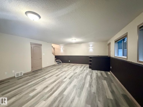 Spacious room featuring wood-finish flooring, two-tone walls, recessed wall lighting, and built-in shelving - 1978 Tomlinson Green Green, Edmonton, AB 