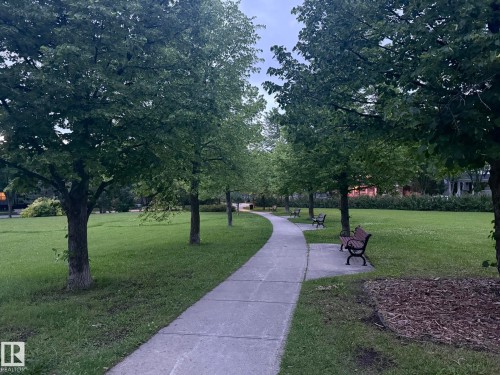 Curved concrete pathway traversing a green space, bordered by mature deciduous trees - 1978 Tomlinson Green Green, Edmonton, AB 