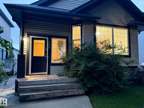 Exterior featuring horizontal siding, a dark trim entry door, and a front window with horizontal blinds - 1978 Tomlinson Green Green, Edmonton, AB 