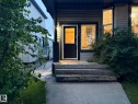 Front entrance featuring a dark paneled door with glass insert, concrete walkway, and wooden stairs leading to a covered porch - 1978 Tomlinson Green Green, Edmonton, AB 