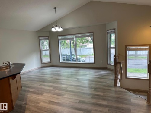 Spacious open-concept room featuring wood-finish flooring, vaulted ceilings, and a bay window configuration - 1978 Tomlinson Green Green, Edmonton, AB 