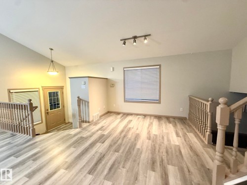 Spacious living area featuring wood-finish flooring, neutral wall tones, and track lighting - 1978 Tomlinson Green Green, Edmonton, AB 