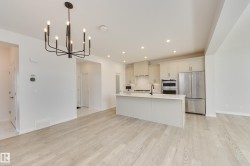 Open-concept kitchen and dining area featuring light wood-finish flooring, a contemporary black chandelier, recessed lighting, a kitchen island with a dark faucet, and stainless steel appliances - 