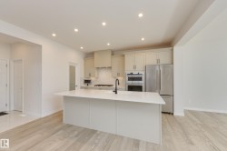Modern kitchen featuring a central island with an integrated sink and black faucet - 