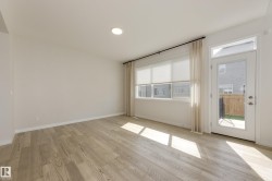 Open interior space featuring wood-finish flooring, recessed ceiling lighting, and a white color palette - 