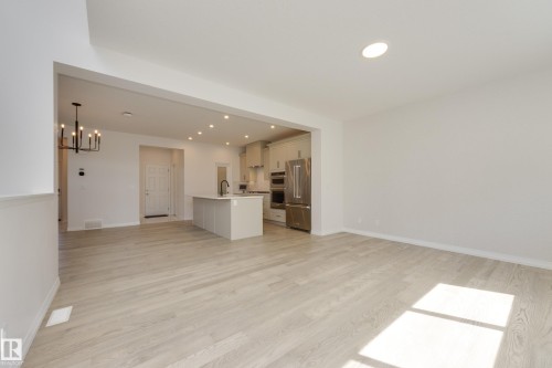 Expansive living area featuring light wood-finish flooring, a modern chandelier, and recessed lighting - 3249 Dixon Way, Edmonton, AB 