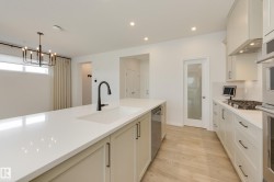 Modern kitchen featuring an extended island with an undermount sink and black faucet - 