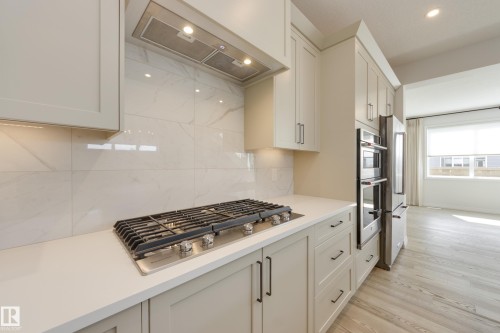 Kitchen featuring a gas cooktop, integrated stainless steel double ovens, and a side-by-side refrigerator - 3249 Dixon Way, Edmonton, AB 