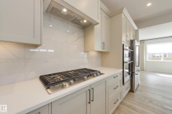Kitchen featuring a gas cooktop, integrated stainless steel double ovens, and a side-by-side refrigerator - 