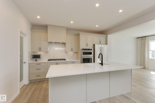 Modern kitchen featuring a large center island with an undermount sink and matte black faucet - 3249 Dixon Way, Edmonton, AB 