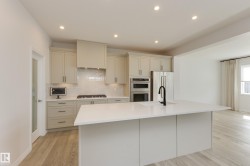 Modern kitchen featuring a large center island with an undermount sink and matte black faucet - 