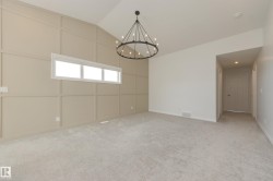Spacious room featuring a vaulted ceiling and a decorative paneled accent wall - 
