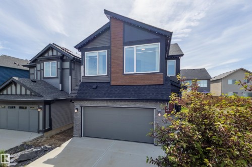 Contemporary two-story exterior featuring dark siding with wood-tone accents - 3249 Dixon Way, Edmonton, AB 