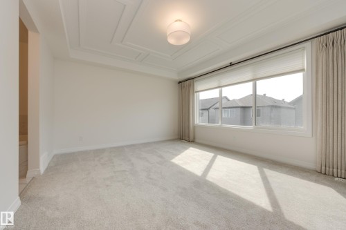 Spacious room featuring light-toned carpeting, a coffered ceiling, and a contemporary ceiling light fixture - 3249 Dixon Way, Edmonton, AB 