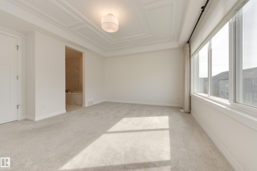 Spacious room featuring broadloom carpeting, large windows, and a coffered ceiling with a flush mount light fixture - 3249 Dixon Way, Edmonton, AB 
