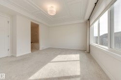 Spacious room featuring broadloom carpeting, large windows, and a coffered ceiling with a flush mount light fixture - 