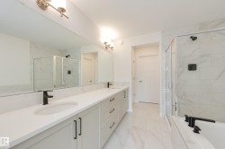 Spacious bathroom featuring a dual vanity with undermount sinks, white countertops, and matte black fixtures - 
