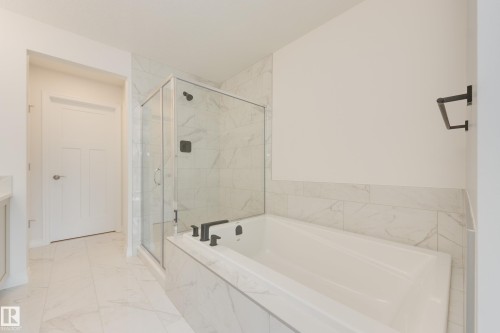 Bathroom featuring a built-in tub with matte black fixtures, a glass-enclosed shower, and large format tile flooring - 3249 Dixon Way, Edmonton, AB 