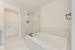Bathroom featuring a built-in tub with matte black fixtures, a glass-enclosed shower, and large format tile flooring - 