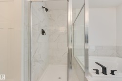 Contemporary shower enclosure featuring clear glass panels and a matte black showerhead - 
