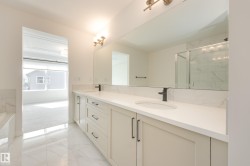 Double vanity with light cabinetry, quartz countertops, and matte black fixtures - 