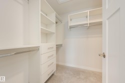 Built-in closet system featuring white shelving, multiple hanging rods, and integrated drawers with brushed nickel hardware - 