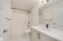 Bathroom featuring a white vanity with an integrated sink, matte black faucet, and a large mirror - 