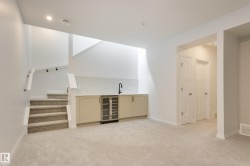 Lower level space featuring plush carpeting and a wet bar with a built-in beverage cooler - 