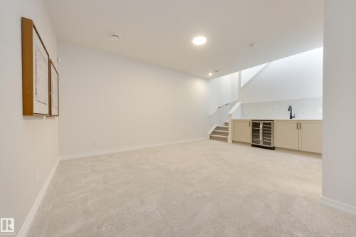 Open concept area featuring light carpeting, recessed lighting, a built-in wet bar with a tile backsplash, and a beverage cooler - 3249 Dixon Way, Edmonton, AB 