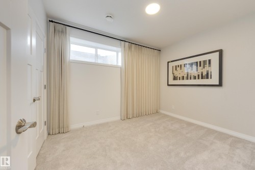 Carpeted room featuring a white paneled door, a horizontal window with drapes, and recessed lighting - 3249 Dixon Way, Edmonton, AB 