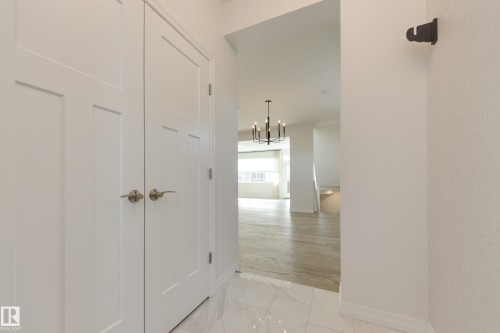 Foyer featuring white paneled double doors with brushed nickel hardware, white tile flooring, and textured wall coverings - 3249 Dixon Way, Edmonton, AB 