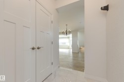 Foyer featuring white paneled double doors with brushed nickel hardware, white tile flooring, and textured wall coverings - 