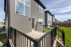 Rear exterior featuring gray horizontal siding, a private deck with black metal railing, and a red exterior door - 