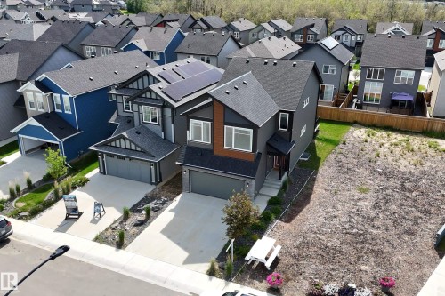 Contemporary-style residence with a dark gray facade, contrasting brown accent paneling, and a two-car garage - 3249 Dixon Way, Edmonton, AB 
