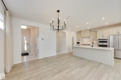 Open-concept living space featuring wood-finish flooring, a modern chandelier, recessed lighting, a kitchen island with a single-basin sink, and stainless steel appliances - 