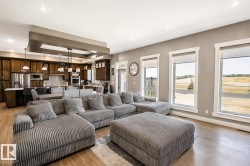 Open-concept living space featuring wood-finish flooring, recessed ceiling lighting, and expansive windows - 