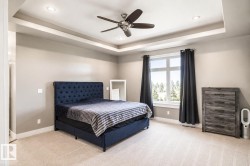 Recessed lighting illuminates a tray ceiling with a central ceiling fan - 