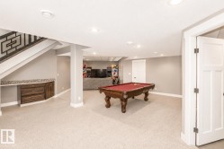 Spacious lower level featuring plush carpeting, recessed lighting, and a built-in wood-finish cabinet with a mosaic tile backsplash - 