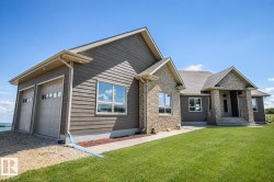 Exterior featuring a two-car garage with panel doors, multi-paned windows, a stone-accented facade, and a covered entry with steps - 