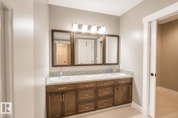 Double vanity featuring wood-finish cabinetry, dual undermount sinks, and a light-toned countertop - 