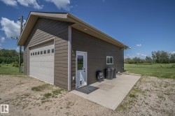 Detached garage featuring horizontal siding, a light-colored garage door with windows, a pedestrian entry door, and a concrete pad - 
